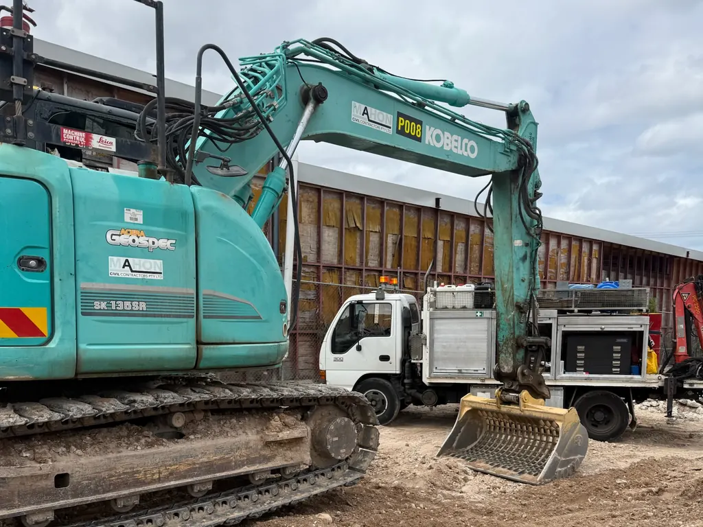 Kobelco excavator on a civil job site with the Nader Diesel Industries service truck parked behind