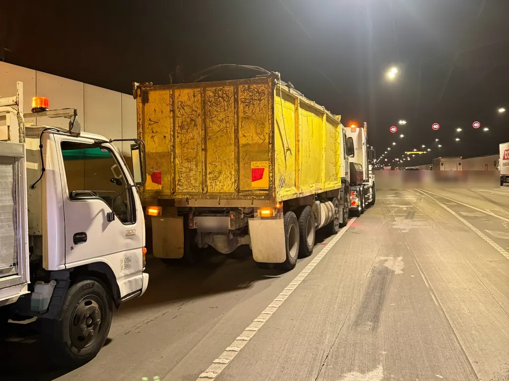 Night-time breakdown callout on a Sydney motorway, with the service truck parked behind a tipper