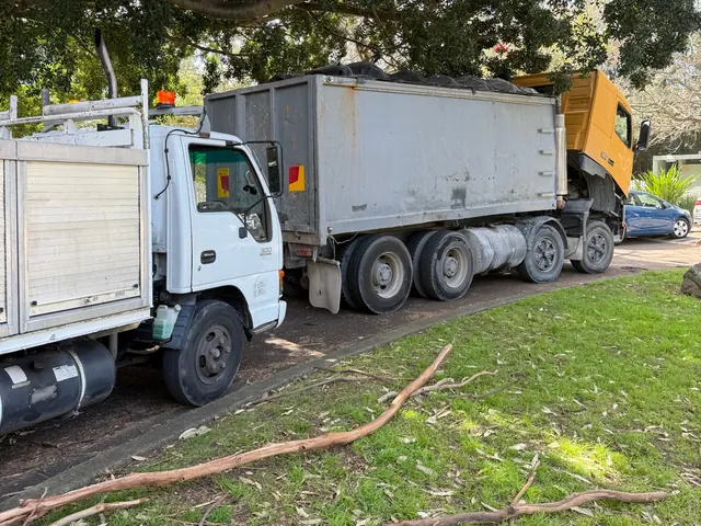 Service truck parked behind a tipper truck with its cab tilted for a roadside repair